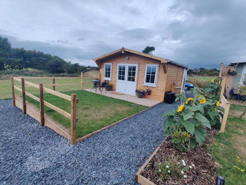 a tiny house with a fence and a garden at Bumble Bee Cabin in Bootle