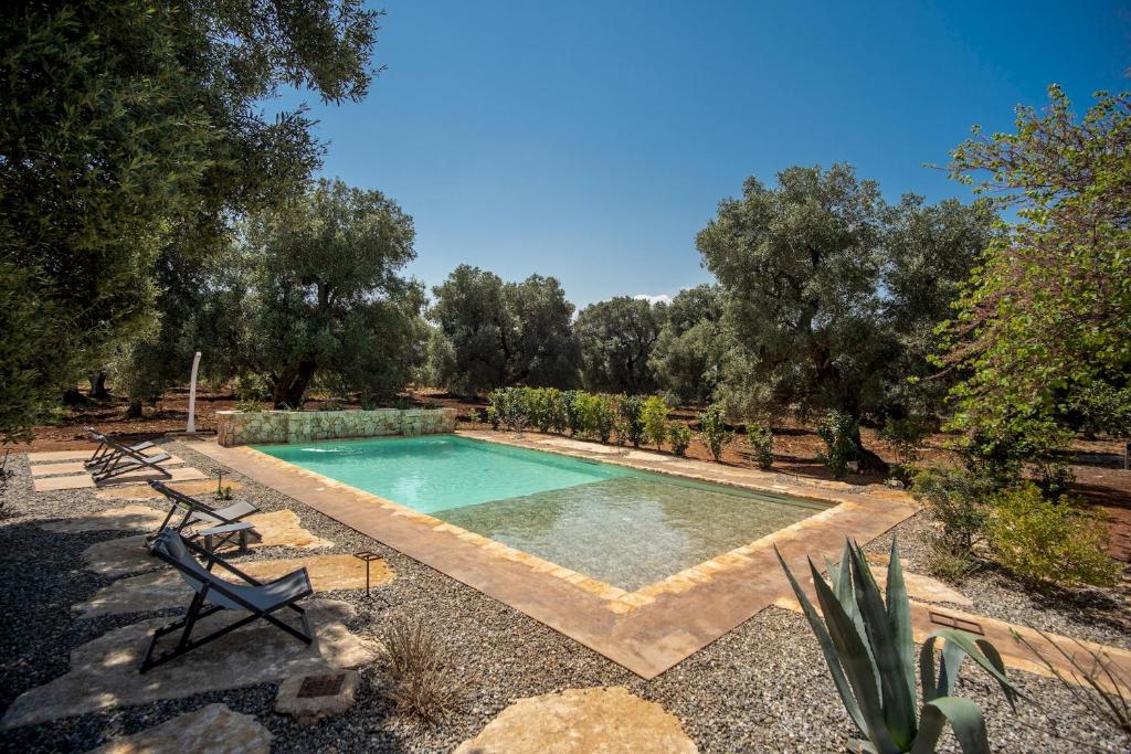 a swimming pool in a yard with chairs and trees at Trulli cicale e olive in Ceglie Messapica
