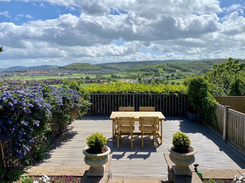a wooden deck with a table and chairs and flowers at Llandudno Boutique style seaside retreat with stunning views in Llandrillo-yn-Rhôs