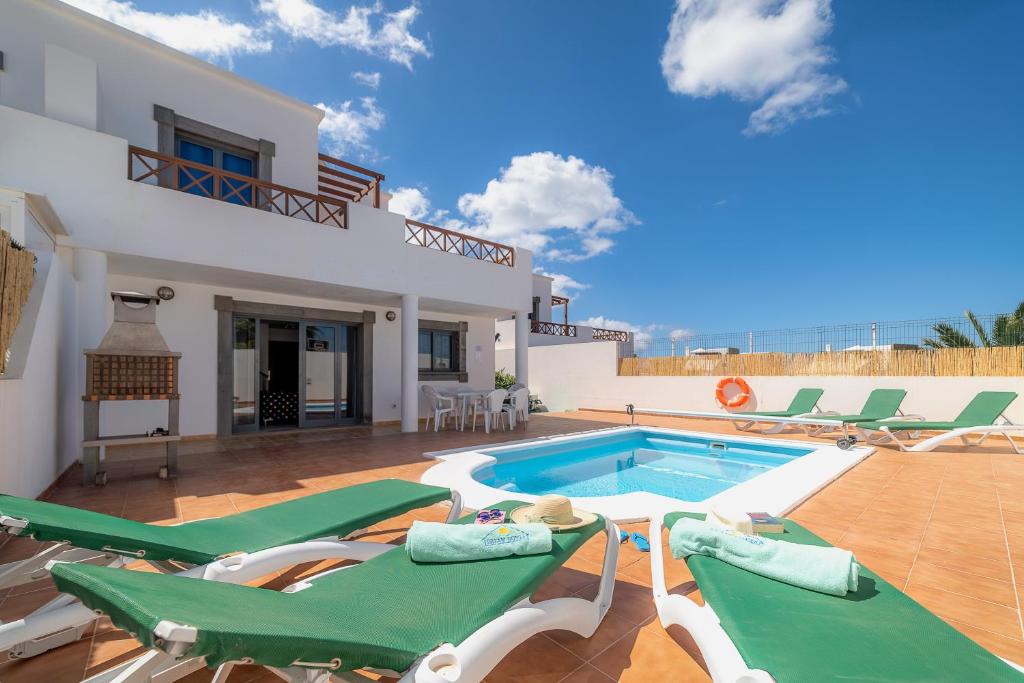 Villa con piscina y sillones verdes en Casa LAGO en Playa Blanca