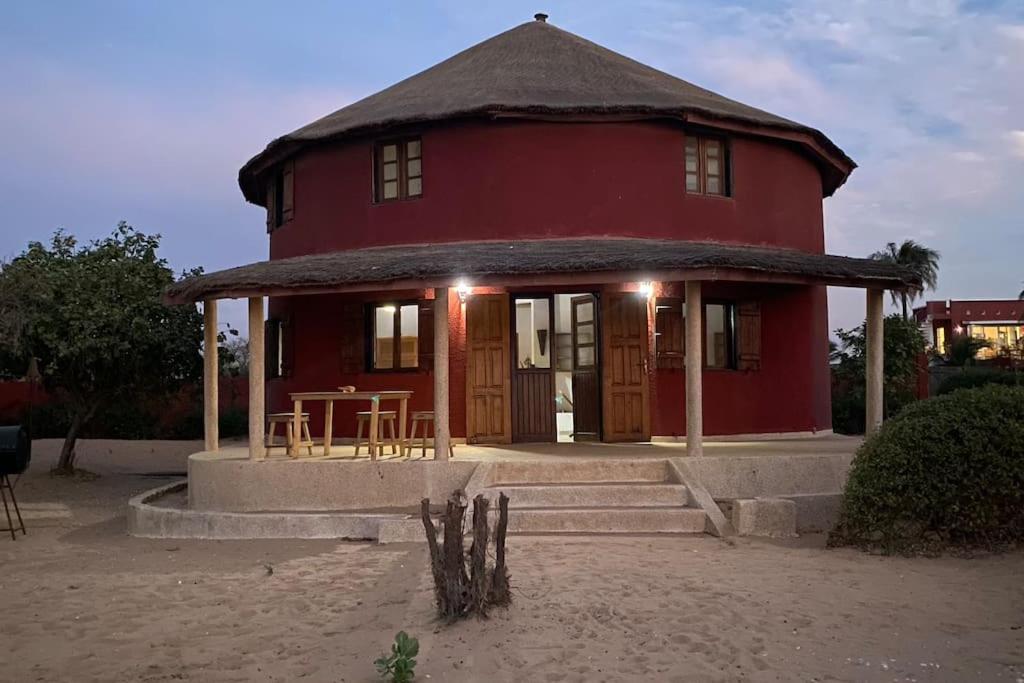 a red house with a table in front of it at Case beach in Ngalou Sessène