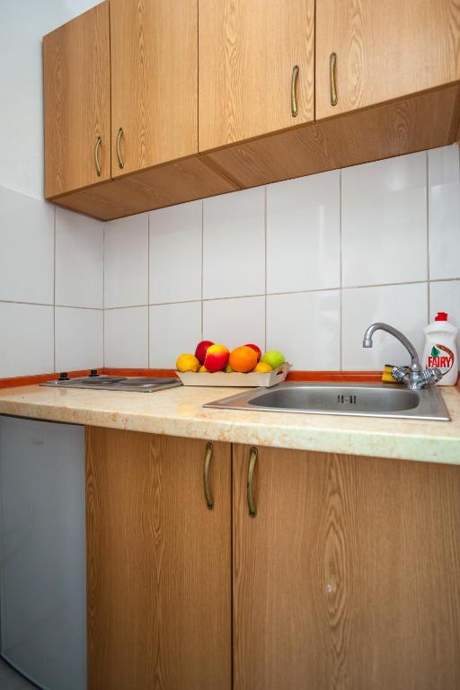 a kitchen with a sink and a bowl of fruit on the counter at Apartments Marko in Tivat