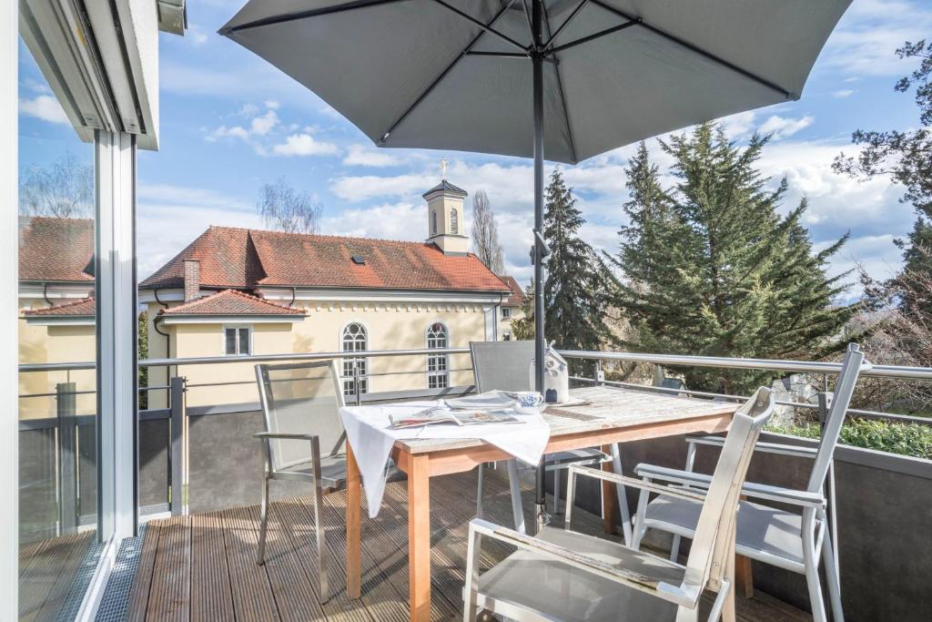 un tavolo in legno e sedie su un balcone con ombrellone di Parkside a Lindau