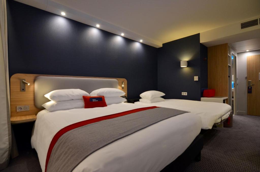 a hotel room with two beds with white pillows at Holiday Inn Express - Paris - CDG Airport by IHG in Roissy-en-France