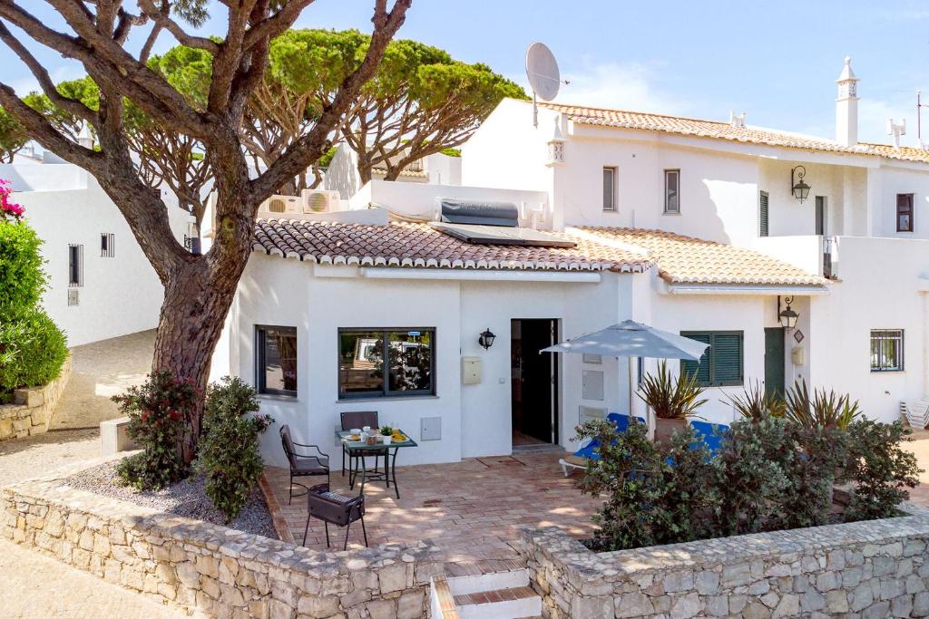 a white house with a tree and a patio at Casa Alessa - Vale de Lobo in Almancil