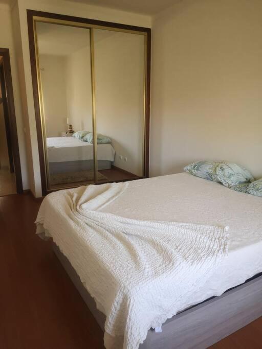 1 dormitorio con cama blanca y espejo en Maravilhoso apartamento T2 Estoi, en Estói