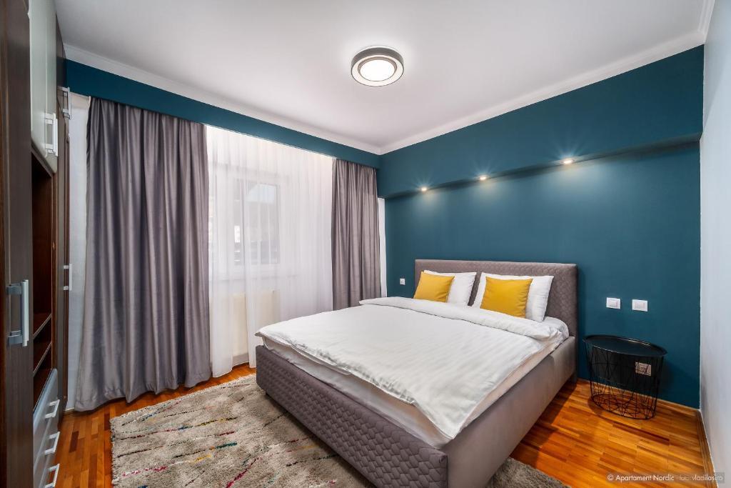 een slaapkamer met een bed met een blauwe muur bij Apartament Nordic in Gura Humorului