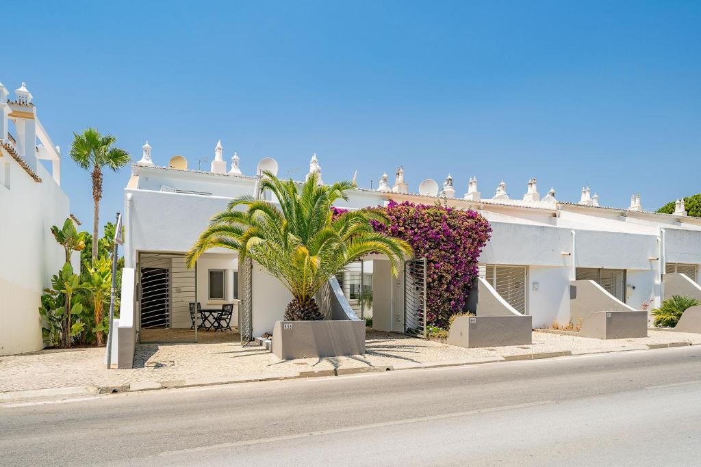 a white building with a palm tree in front of it at Casa Maya - Vale do Garrão in Quinta do Lago