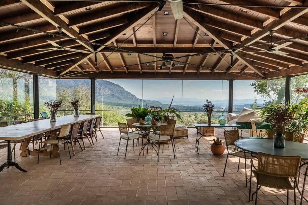 a large patio with tables and chairs and a large window at HHBCN Villa El Castell in El Bruc