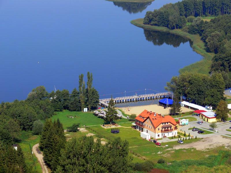 a house on a hill next to a body of water at Hotel Słoneczny Brzeg in Biskupiec