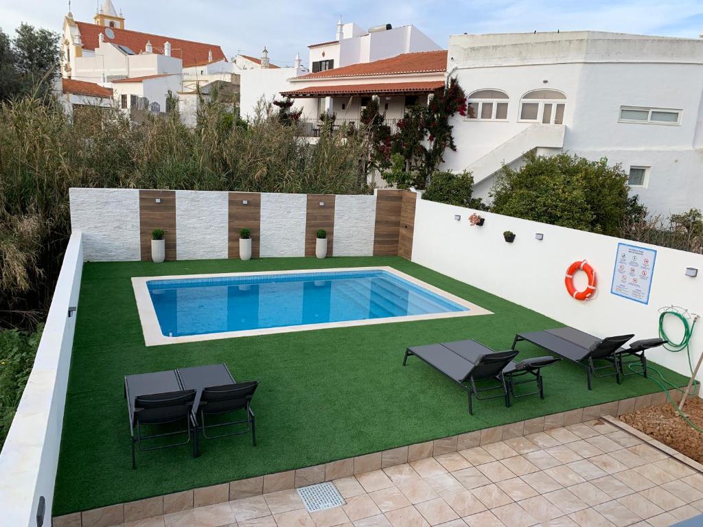 un patio trasero con piscina y césped verde en Casa do Ti-Zé, en Pêra