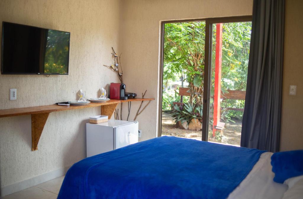 um quarto com uma cama azul e uma porta de vidro deslizante em La em casa Noronha em Fernando de Noronha