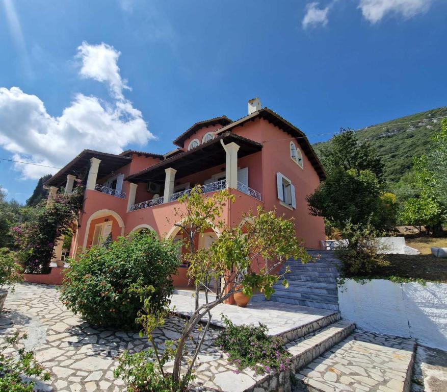 una gran casa roja con una colina al fondo en Atisis Apartments, en Benitses