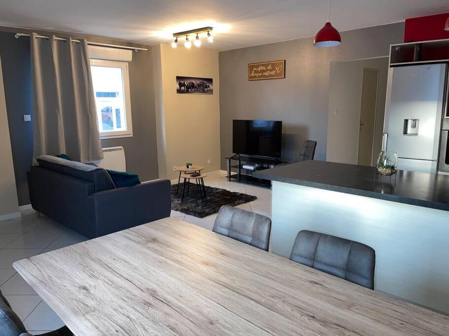 a kitchen and living room with a table and a couch at Appartement plein centre ville st dié des Vosges in Saint Die