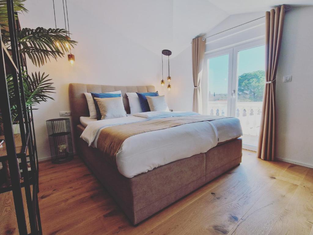 un grande letto in una stanza con una grande finestra di Olivea Luxury Suites a Fažana