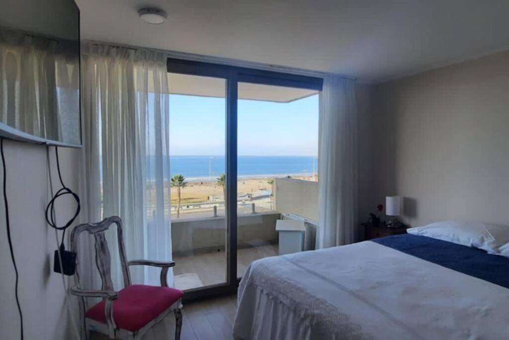 a bedroom with a bed and a view of the ocean at Departamento frente al mar in Coquimbo
