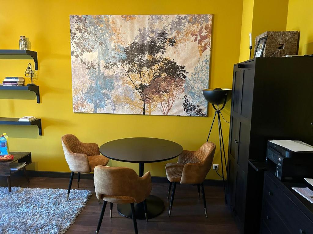 FewoCompany في لايبزيغ: غرفة صفراء مع طاولة وكراسي ودهان