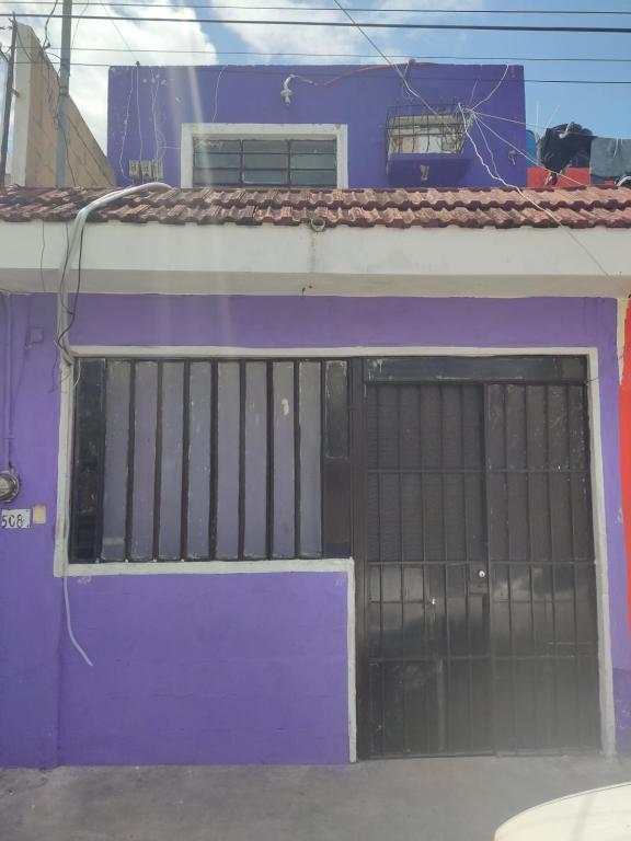 um edifício roxo com uma porta com barras em Hostal Maruvillas em Mérida