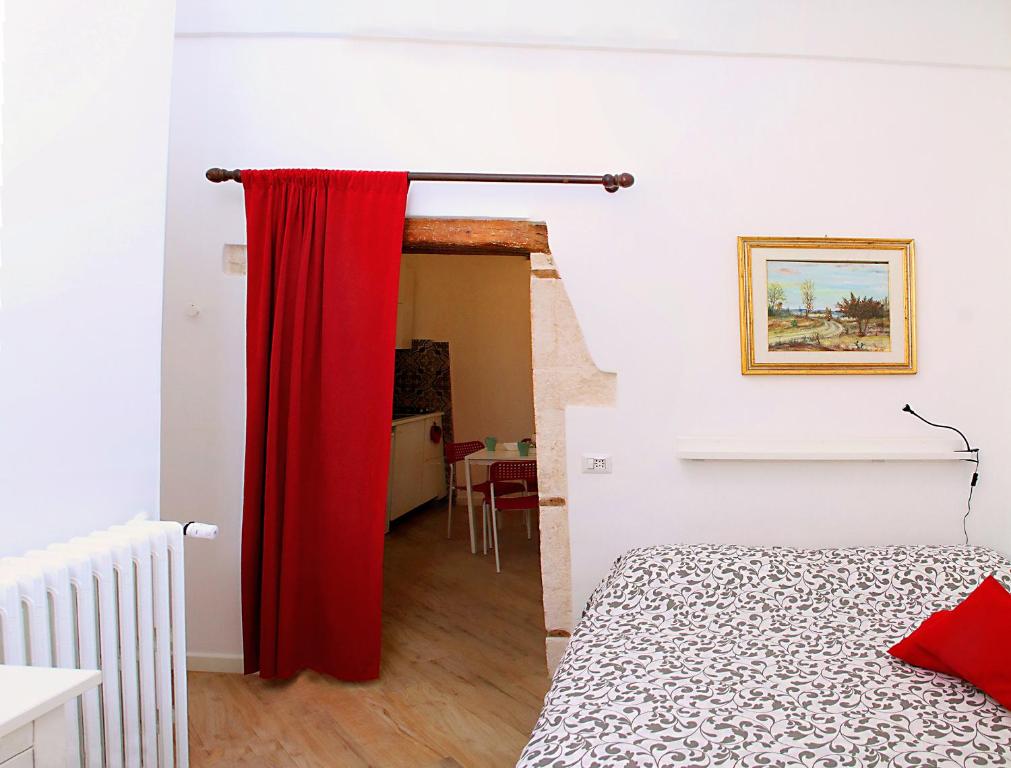 een rood gordijn in een witte kamer met een bed bij Lo studio di Nonno in Noci