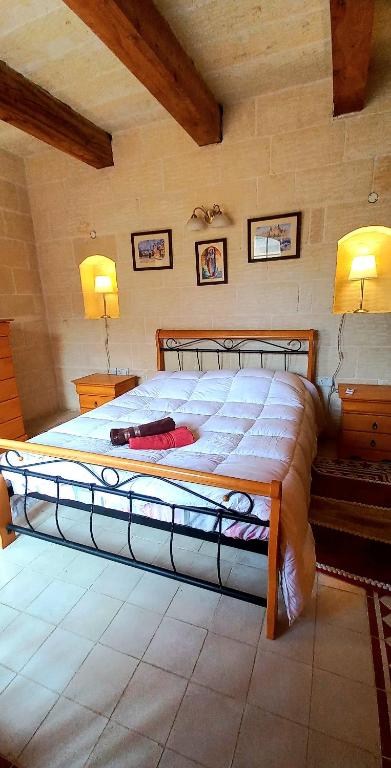 a large bed in a bedroom with two lights on at Ta Majsi farmhouse with indoor heated pool in San Lawrenz