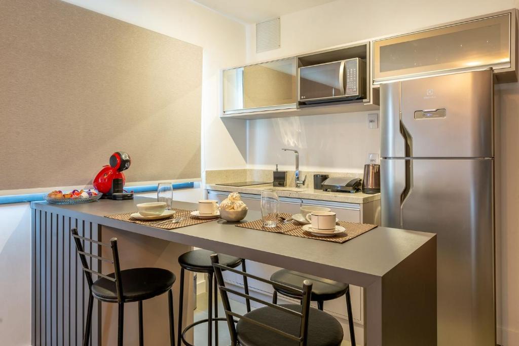 uma cozinha com um balcão com cadeiras e um frigorífico em LIV - Apartamento 907 em Porto Alegre