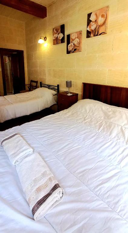 a bedroom with two beds with white sheets at Ta Majsi farmhouse with indoor heated pool in San Lawrenz