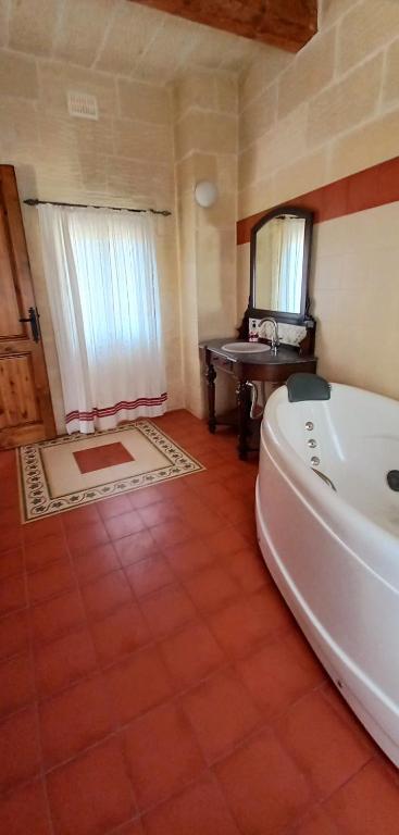 a bathroom with a tub and a sink and a mirror at Ta Majsi farmhouse with indoor heated pool in San Lawrenz