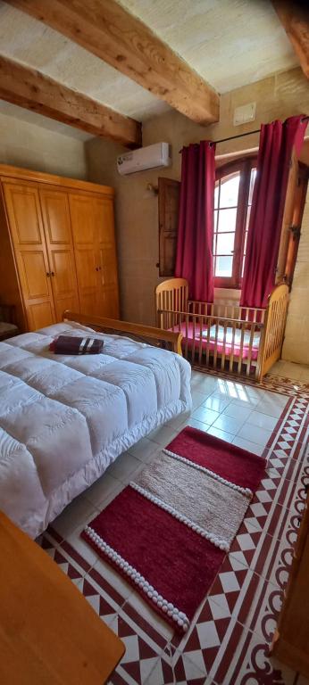 a bedroom with a large bed and red curtains at Ta Majsi farmhouse with indoor heated pool in San Lawrenz