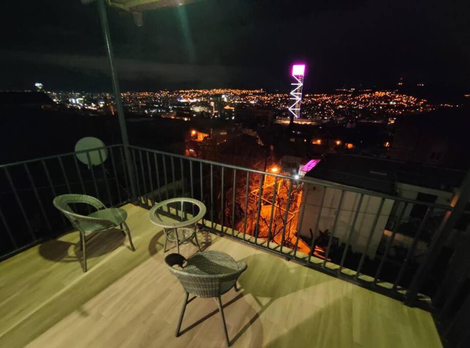 balcón con sillas y vistas a la ciudad por la noche en Luca's Apartment in old tbilisi, en Tiflis