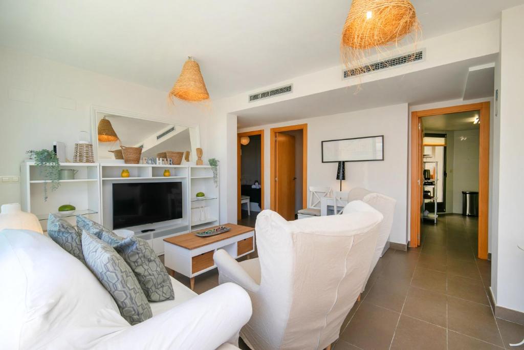 a living room with white furniture and a tv at Homeincalpe Borumbot in Calpe