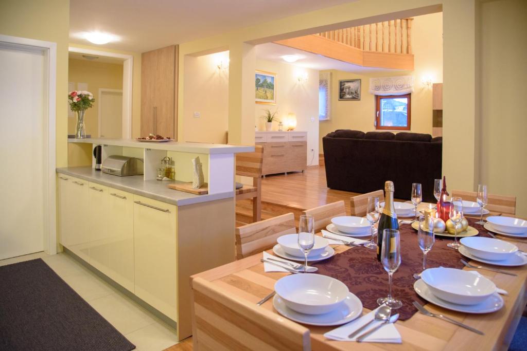 cocina y sala de estar con mesa con platos y copas de vino en Villa Bjelolasica, en Jasenak