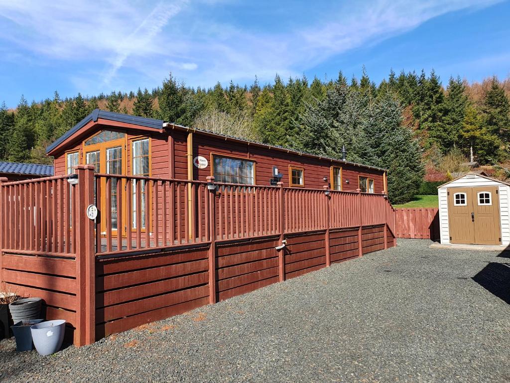 GlendevonにあるPoppy Lodge Glendevon Scotlandの塀とガレージ付きの木造キャビン