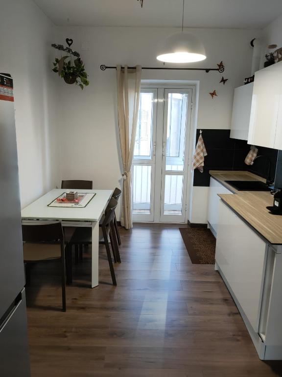 cocina con mesa, mesa blanca y puerta en Casa Vacanze Celine a due passi dal mare en Savona