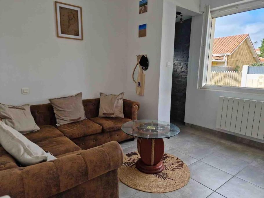 ein Wohnzimmer mit einer Couch und einem Glastisch in der Unterkunft Appart tout à portée de tongs! in Mimizan