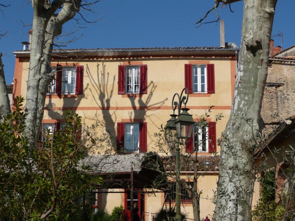 een gebouw met rode ramen en bomen ervoor bij Auberge de Correns in Correns