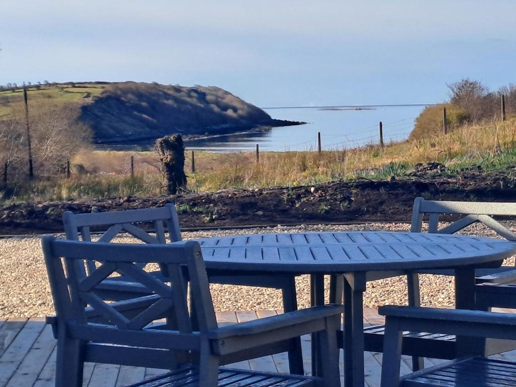 a picnic table with two chairs and a view of the ocean at Blaneys Coastal Cottage in Mountcharles