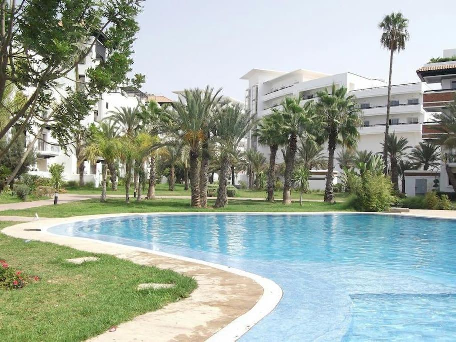 une piscine bordée de palmiers et un bâtiment dans l'établissement Marina Agadir, à Agadir