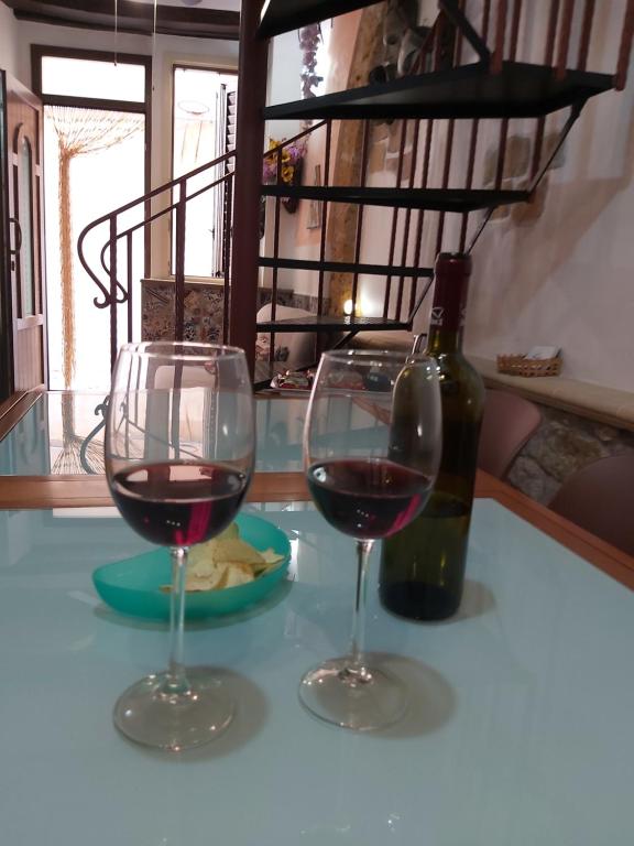due bicchieri di vino seduti su un tavolo con una bottiglia di vino di Appartamento Seminario a Cefalù