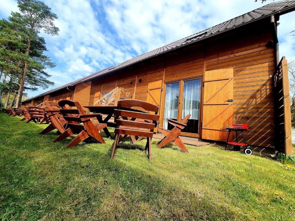 a row of wooden benches in front of a log cabin at Ośrodek Wczasowy Maliwa in Jarosławiec