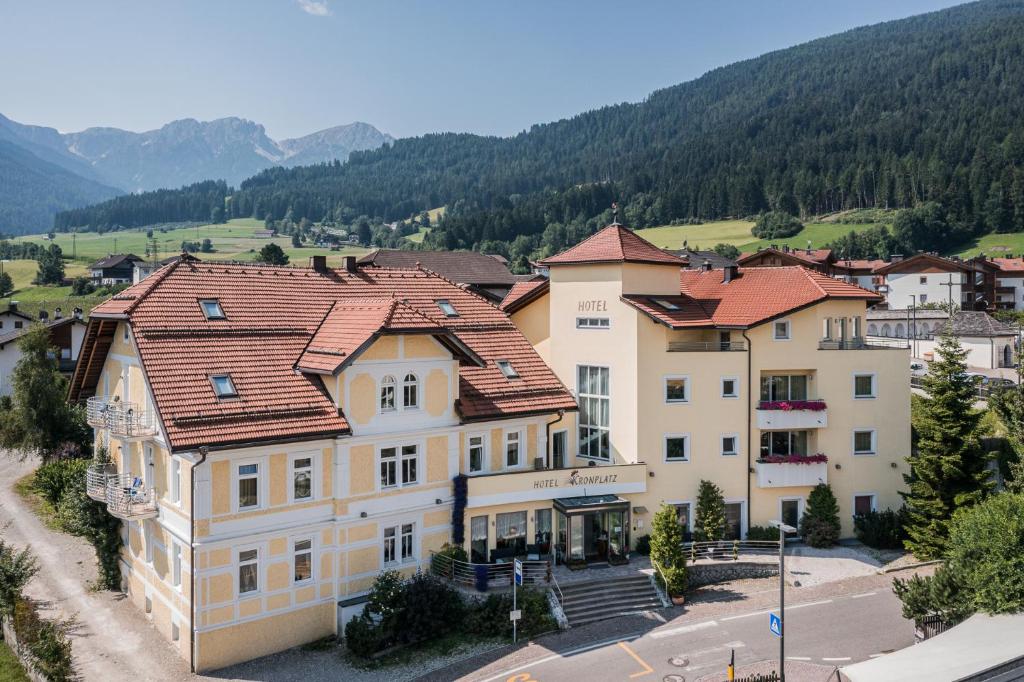 a building in a town with mountains in the background at Hotel Kronplatz in Valdaora