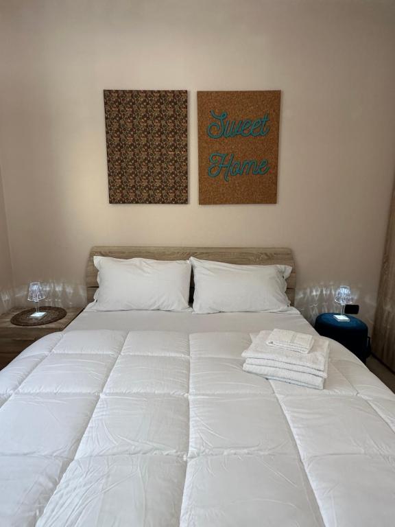 1 cama blanca en un dormitorio con 2 cuadros en la pared en Sweet Home en Savigliano