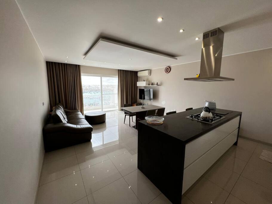 eine Küche und ein Wohnzimmer mit einem Sofa und einem Tisch in der Unterkunft Marsaxlokk SeaView 2 Bedroom Penthouse in Marsaxlokk