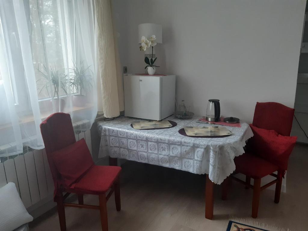 stół z dwoma czerwonymi krzesłami i mikserem w obiekcie Mieszkanie na mazurach 2 w mieście Kętrzyn