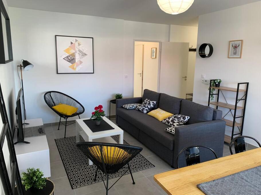 ein Wohnzimmer mit einem Sofa und einem Tisch in der Unterkunft Appart T3 Standing - Terrasse - 2 Parkings in Montpellier