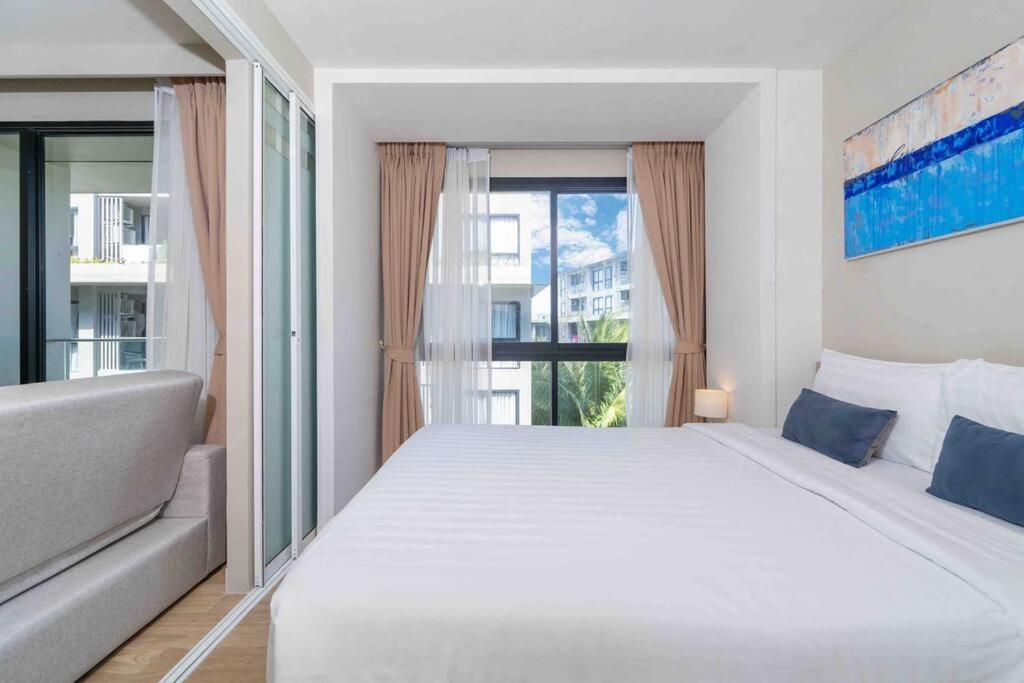 a bedroom with a large bed and a large window at Diamond Resort Phuket Bangtao in Phuket