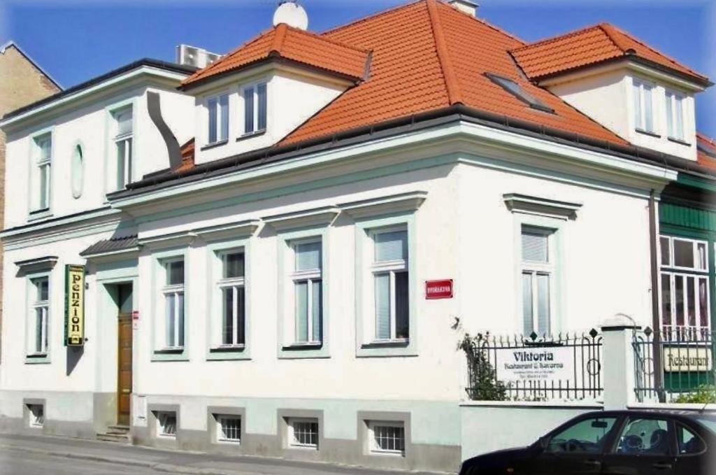 a white building with an orange roof on a street at Penzion Viktoria in Znojmo