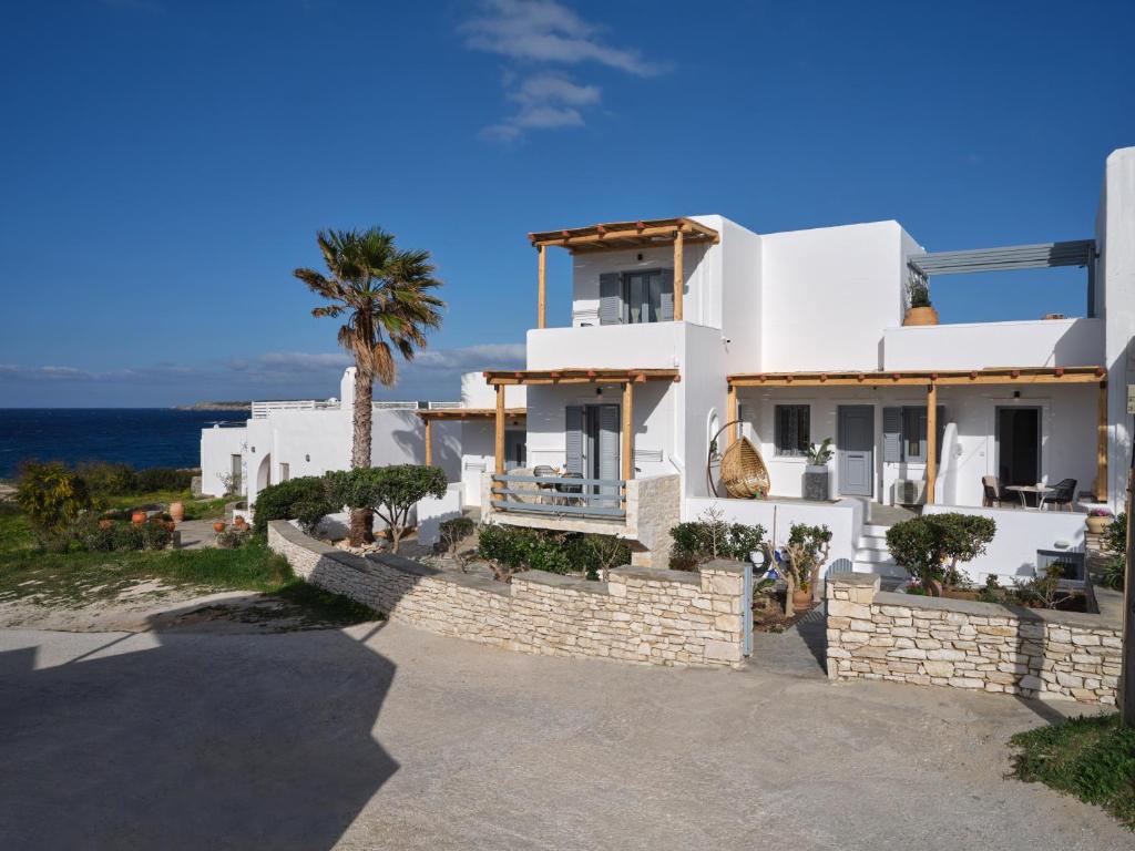 uma casa branca com uma palmeira e o oceano em Ariti Seaside Residence em Naousa