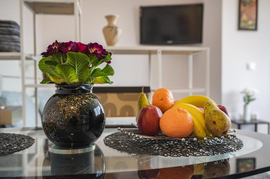 Paradise Guest Apartment في صوفيا: مزهرية مع الزهور والفواكه على طاولة
