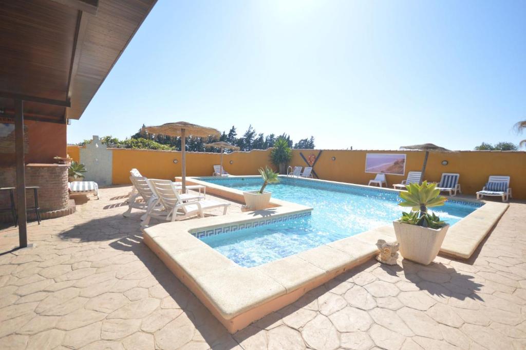 una piscina con sedie e ombrellone su un patio di Casa Samuel Mayorazgo con piscina compartida a Cadice