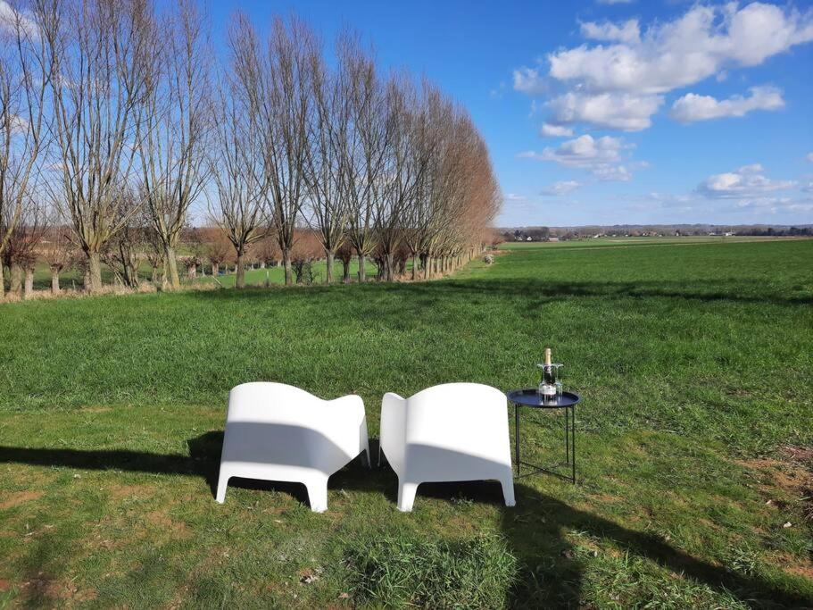 two white chairs and a table in a field at Komo Hill Stays - guestroom Komo Cosy in Kruisem